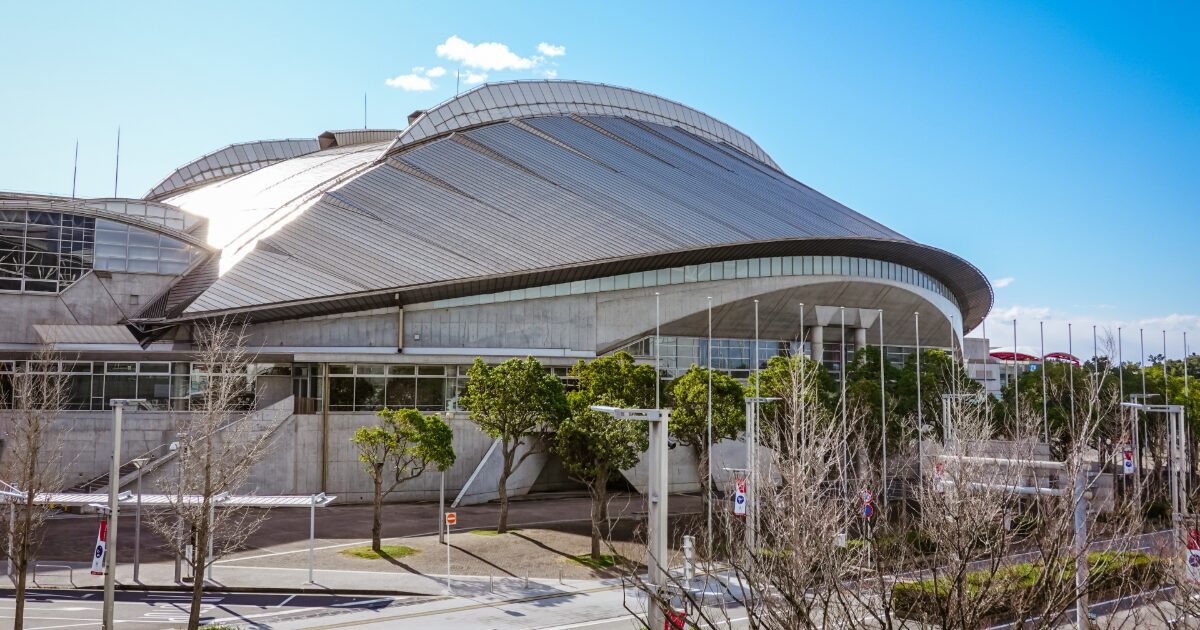 大型ドーム型施設の外観と青空の都市景観