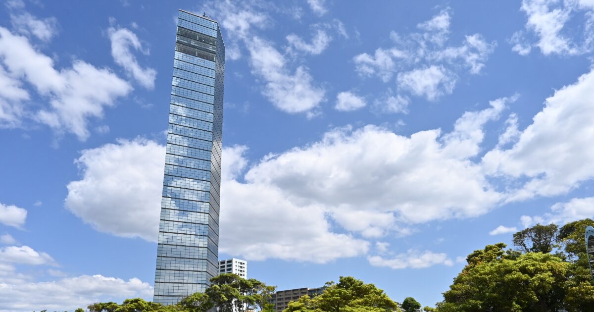 青空にそびえるガラス張りの高層タワービル