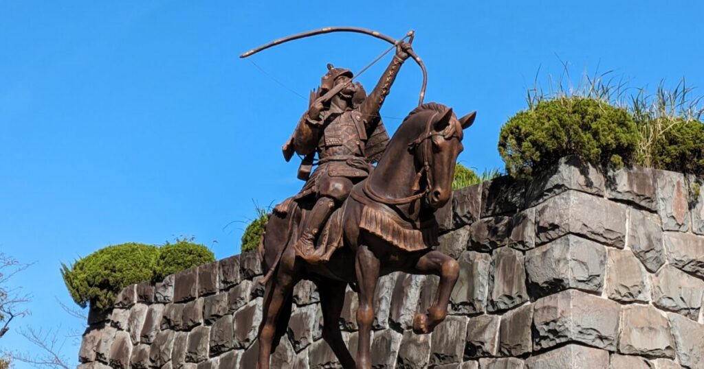 弓を構える騎馬武者像と石垣の歴史的モニュメント