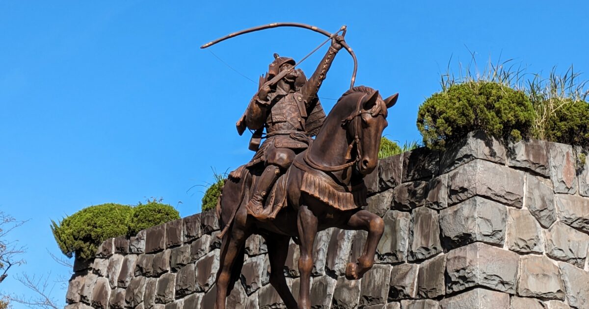 弓を構える騎馬武者像と石垣の歴史的モニュメント