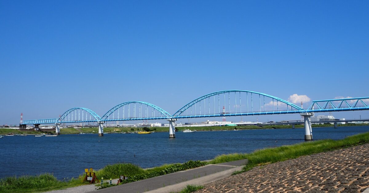 青いアーチ橋が川を横断する開放的なリバーサイド風景