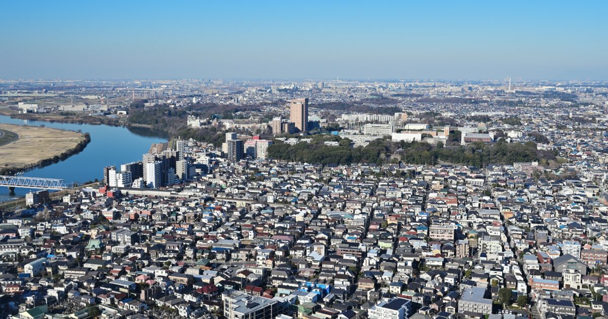 河川沿いに広がる住宅地と高層建物を上空から捉えた都市風景