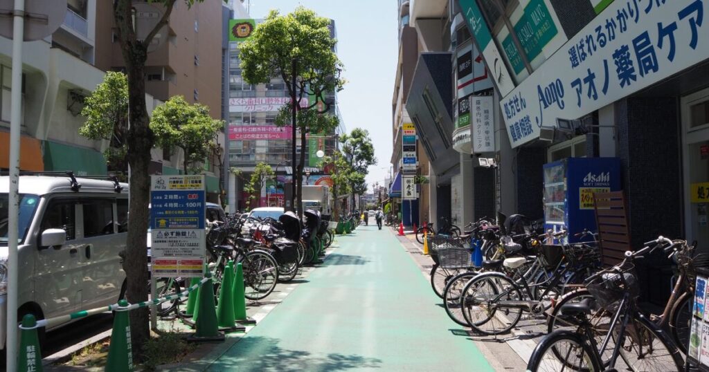 自転車が並ぶ商店街の通りと店舗看板が続く街並み