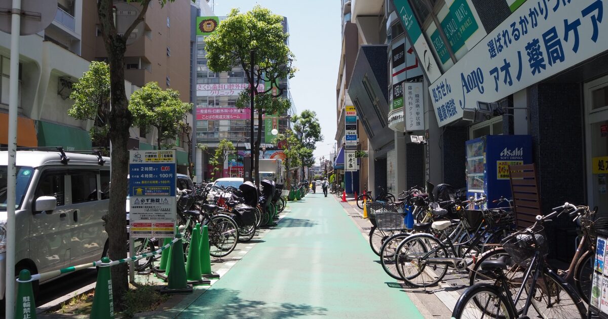 自転車が並ぶ商店街の通りと店舗看板が続く街並み