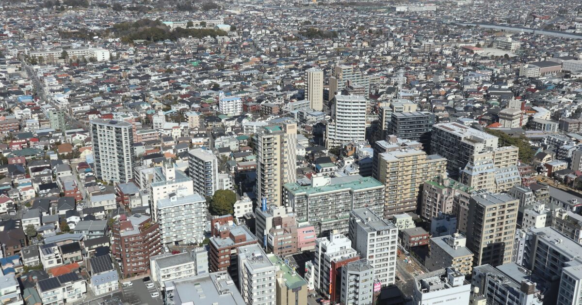 中低層ビルと住宅が密集する都市の全景を上空から撮影