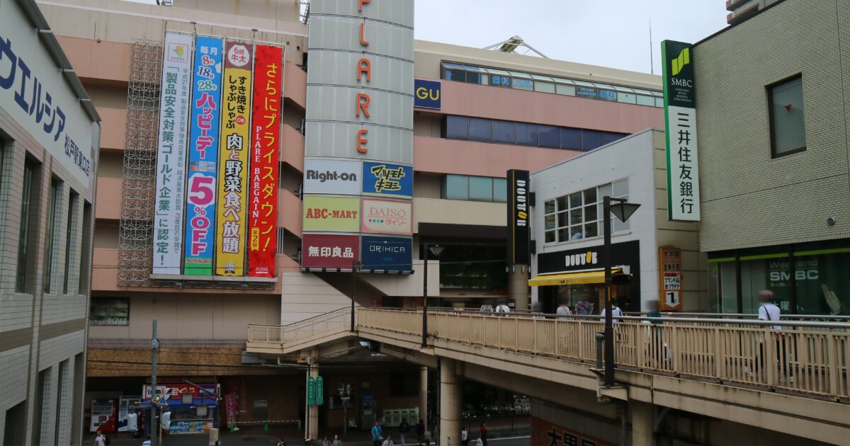 商業施設と歩道橋が交差する駅前の都市景観