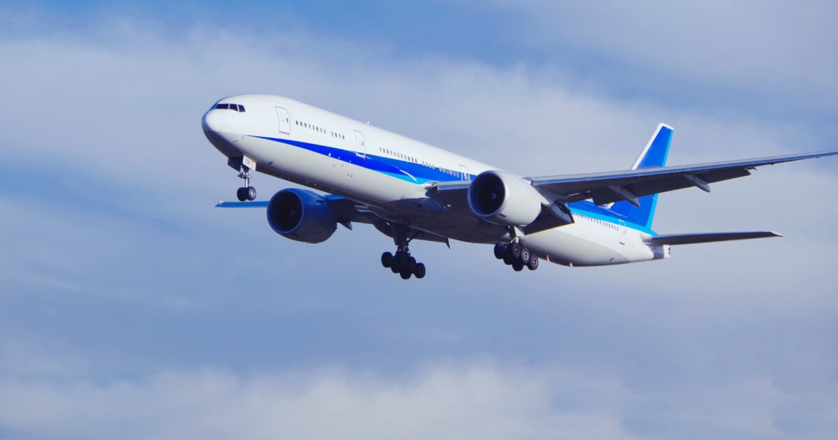 青空を背景に着陸態勢の旅客機が飛行する様子
