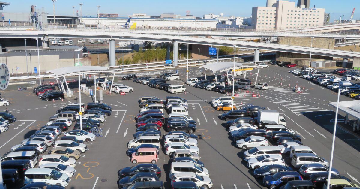 空港駐車場に整然と並ぶ多数の車と高架道路