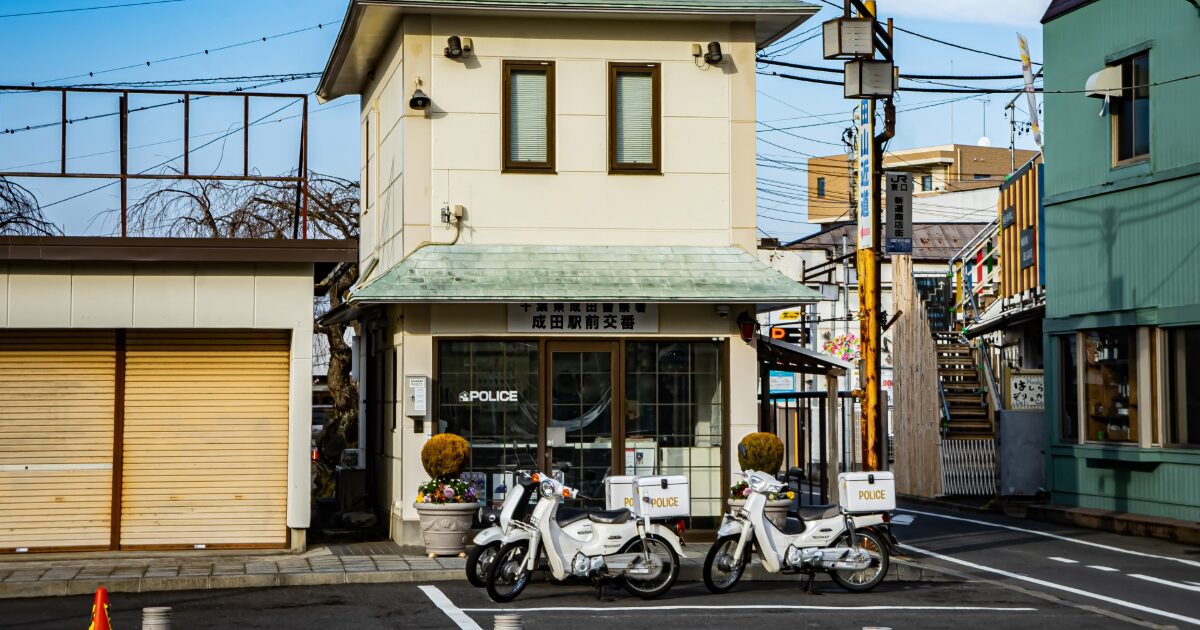 日本の交番前に停車する警察バイクと街並み