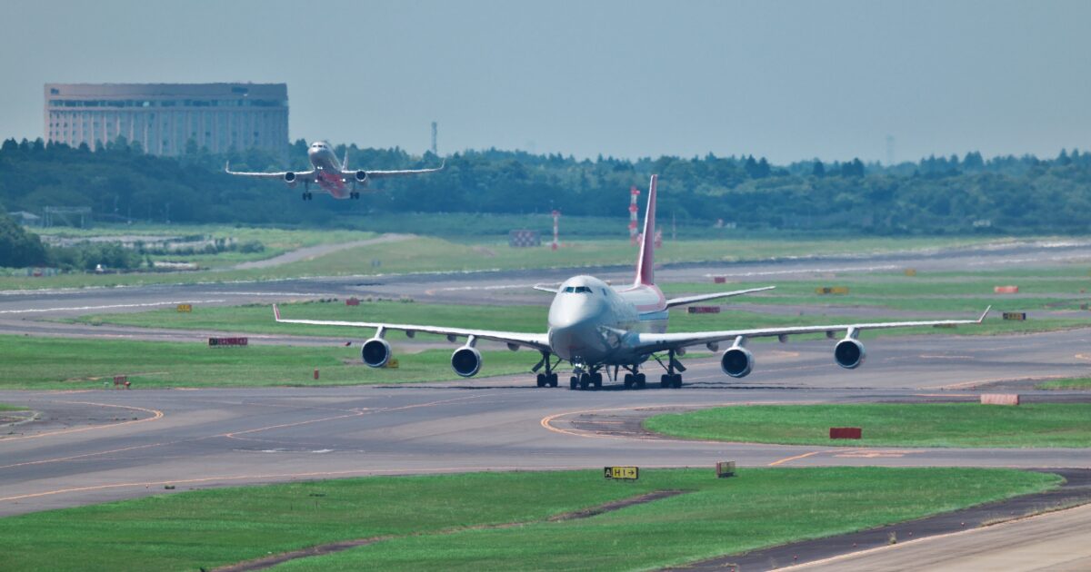 滑走路を走行する大型旅客機と離陸する飛行機